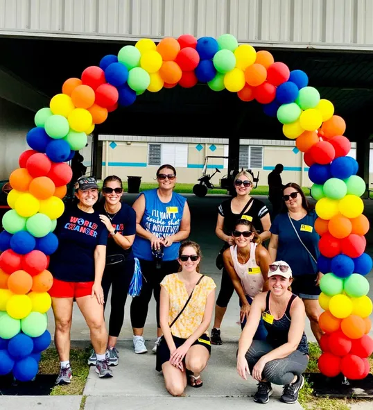 A large rainbow balloon arch built by Cheerioograms at an outdoor community event.