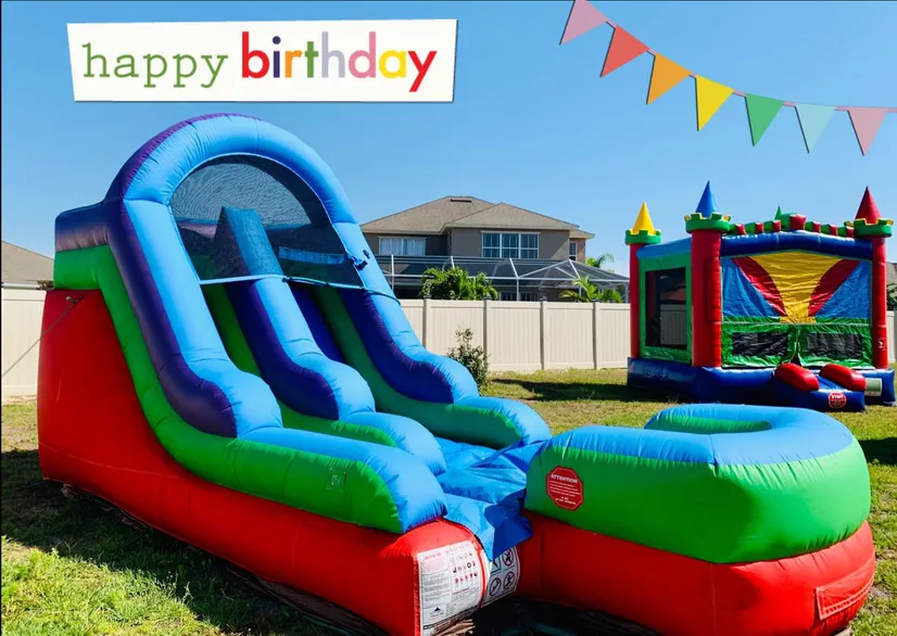 An inflatable water slide and a bounce house castle set up on a sunny backyard lawn.